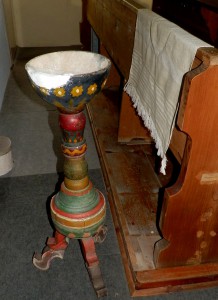 Výrazně barevná a lidovými ornamenty zdobená, neuměle vyřezaná dřevěná křtitelnice se nalézá v toleranční modlitebně augsburského vyznání v Hrubé Vrbce. 